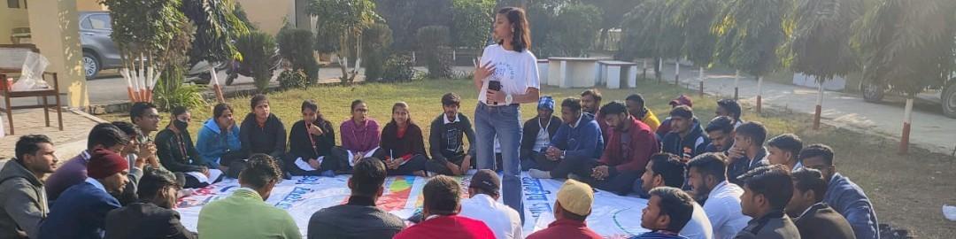 Sheetal leading a large circle of young people in an outdoor session